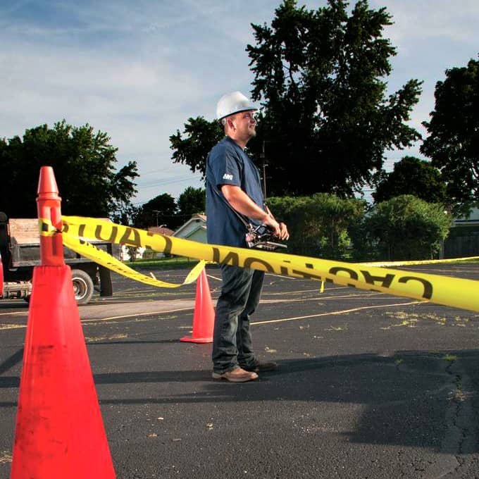 Roofing Installer Next To Orange Cones and Caution Tape